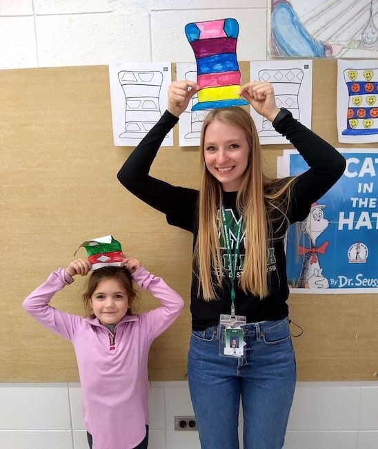 student and her teacher wearing colorful paper hats