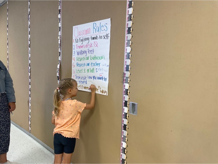 student writing on a paper hanging on wall